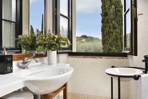 A bathroom with a large window, a white sink, a smaller sink, and a potted plant. - Relais Villa Monte Solare Wellness & SPA (Panicale)