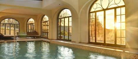 An indoor swimming pool with arched windows and a skylight.