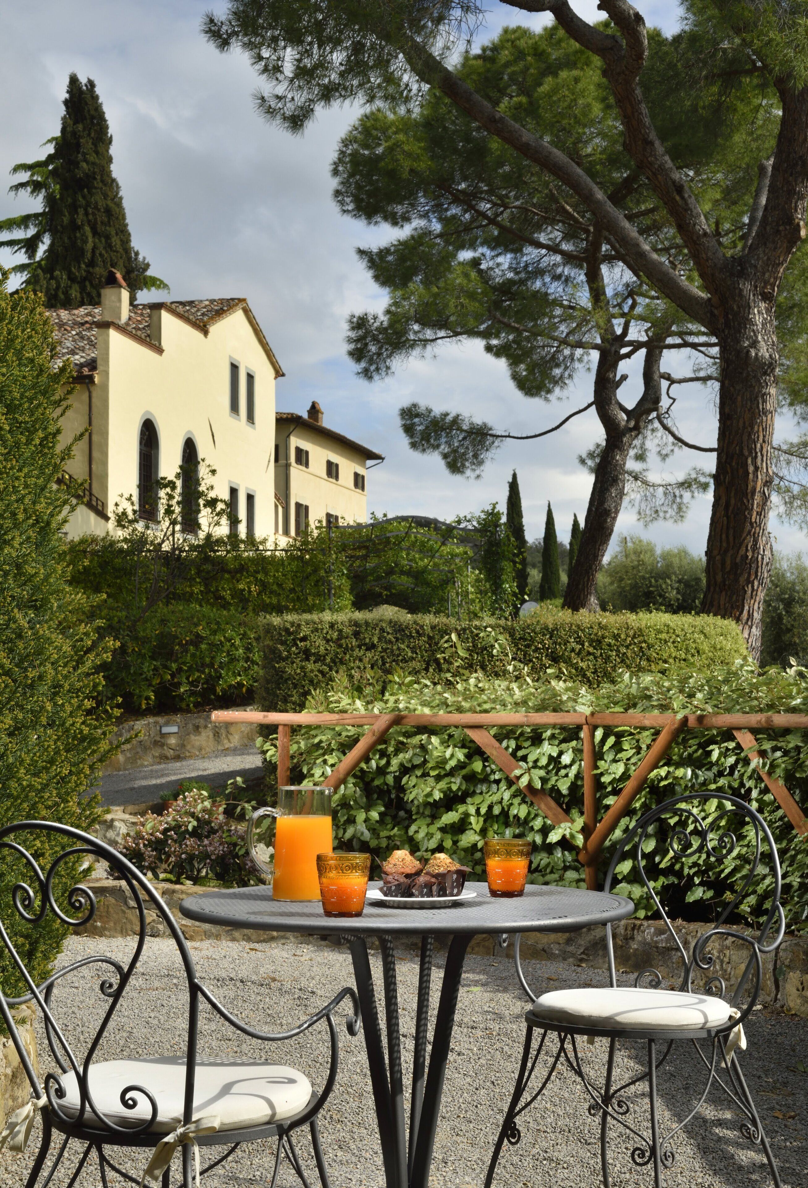 Eine Terrasse mit Tisch und Stühlen, ein Glas Orangensaft und ein Teller Kekse.