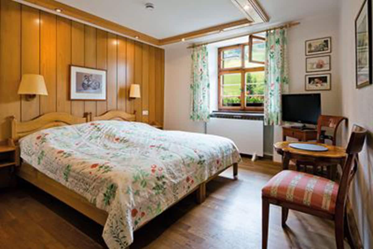 Een slaapkamer met een houten bed, een bureau, een stoel en een televisie.