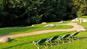 A grassy area with a dirt path and green lawn chairs. - Romantik Hotel Spielweg (Münstertal)