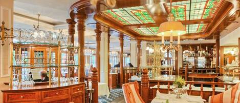 Un lobby de hotel lujoso con muebles de madera ornamentados, un área de bar y un techo de vitrales.