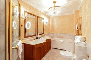 Un baño lujoso con tocador doble, un espejo grande, una araña y una bañera.