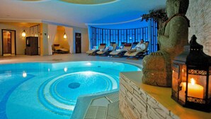 A serene indoor swimming pool with lounge chairs and a Buddha statue. - SEETELHOTEL Ahlbecker Hof (Heringsdorf)