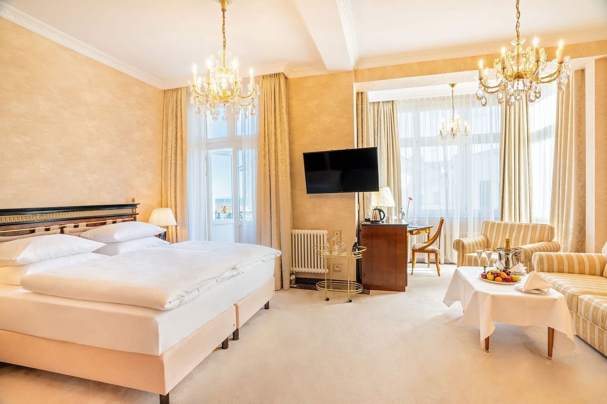 Une chambre d’hôtel avec un grand lit, un bureau, une télévision et un coin repas avec une table dressée pour deux personnes.