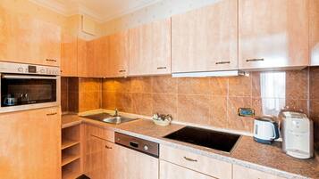 A kitchen with wooden cabinets, a Bosch dishwasher, a sink, and a coffee maker.