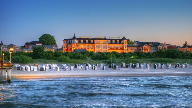 A waterfront hotel with a large building, a beach with sun loungers, and a pier. - SEETELHOTEL Ahlbecker Hof (Heringsdorf)