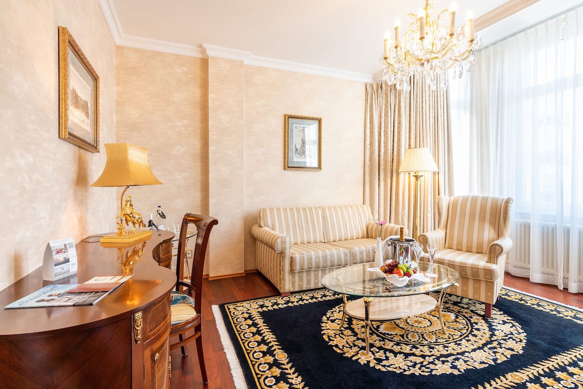 Un salon bien aménagé, avec un canapé, des fauteuils, une table basse et un lustre.