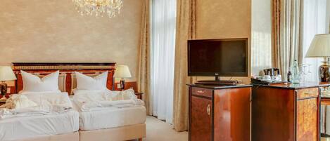 A hotel room with a double bed, a TV, a wooden cabinet, and a chandelier.
