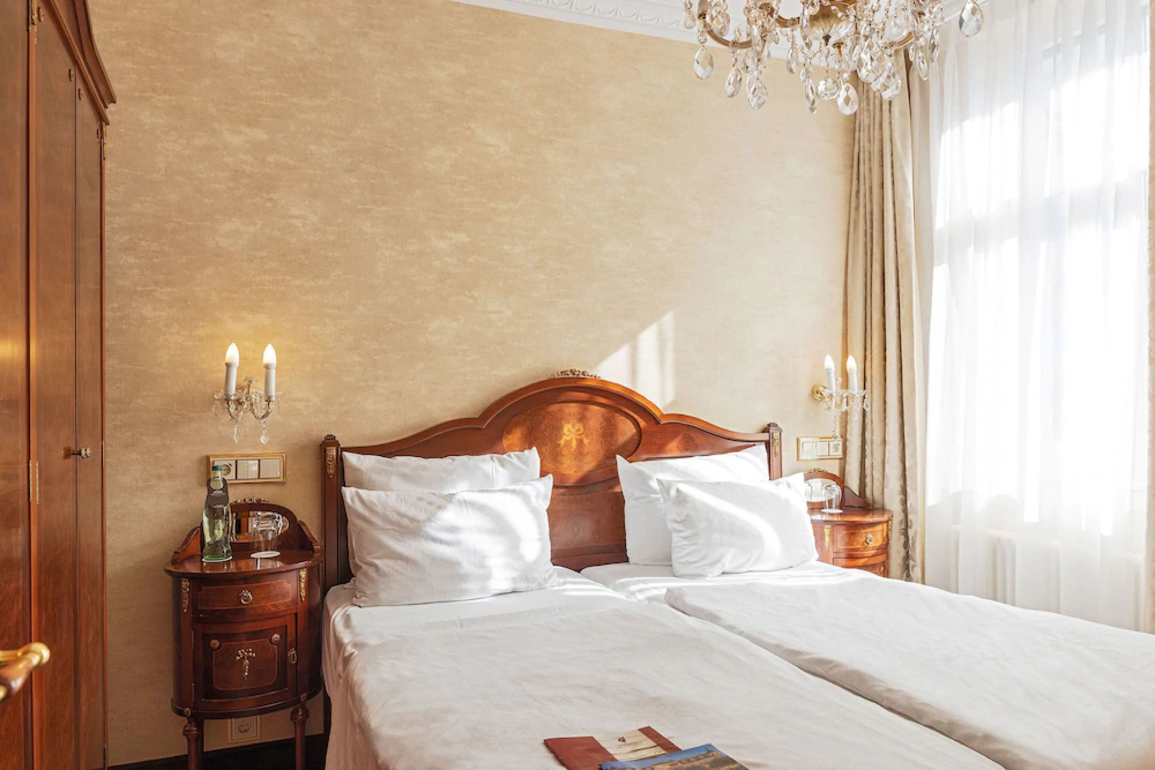 A double bed with white linens, a wooden headboard, and bedside tables with lamps.