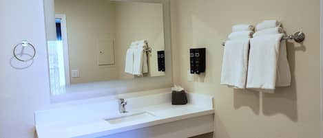 A bathroom with a white sink, a mirror, and two towel racks with towels.