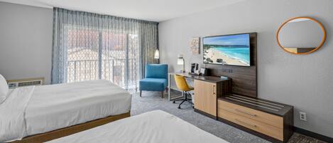 A hotel room with two beds, a desk with a chair, a TV, and a large window with curtains.