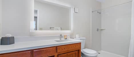 A modern bathroom with a white sink, wooden vanity, and a glass shower enclosure.