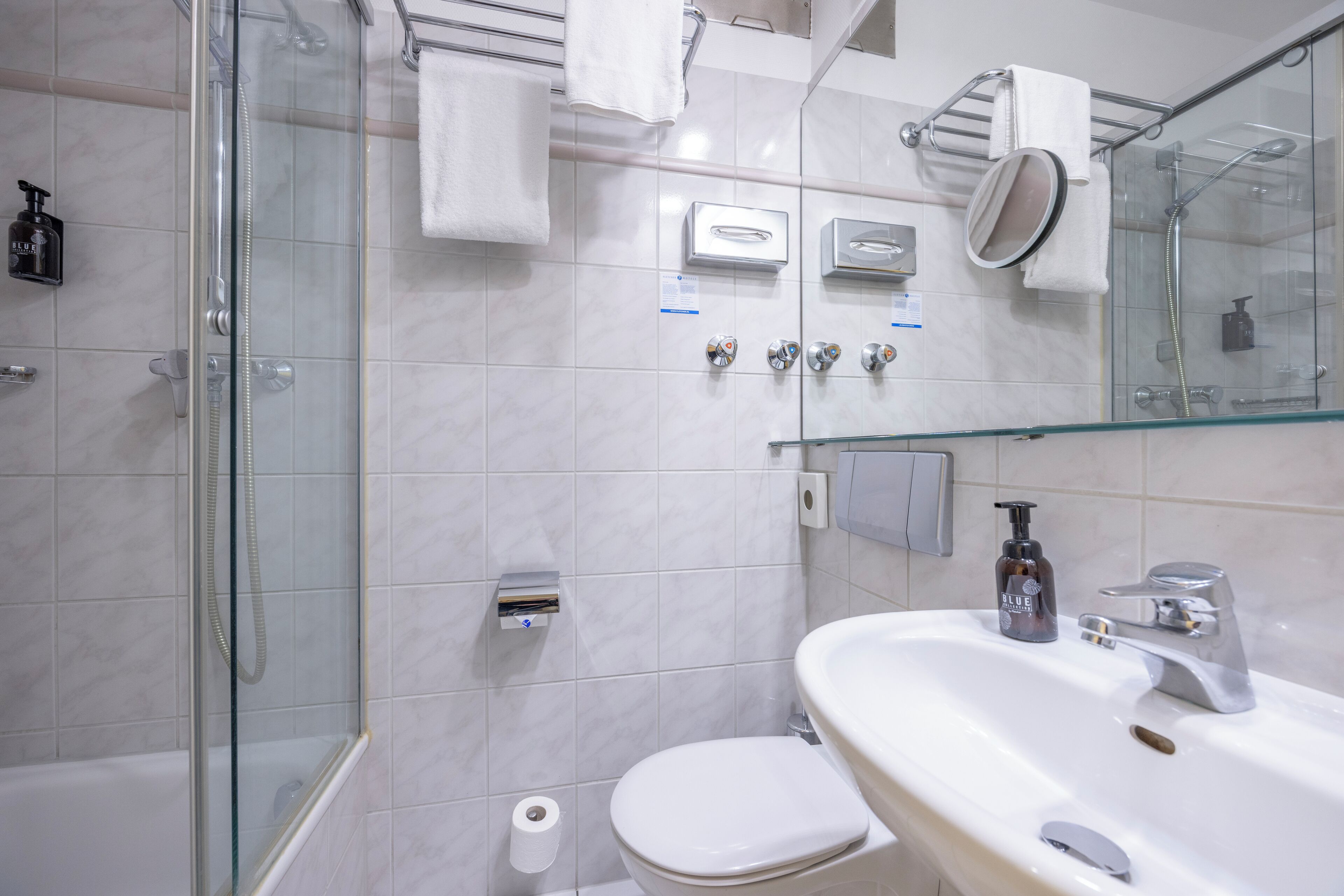 A modern bathroom with a glass-enclosed shower, a white toilet, a sink with a mirror, and a towel rack.
