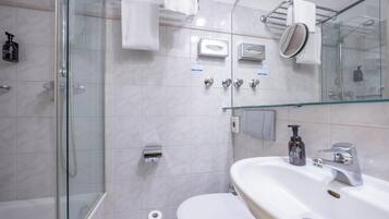 A modern bathroom with a glass-enclosed shower, a white toilet, a sink with a mirror, and a towel rack.