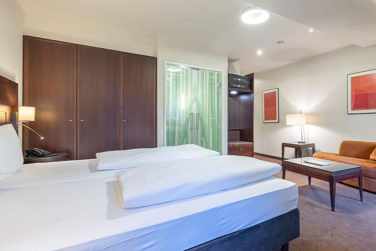 Une chambre d’hôtel avec un grand lit, un bureau, un canapé et une armoire.