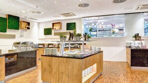 A modern cafe with a wooden counter, glass display cases, and potted plants.