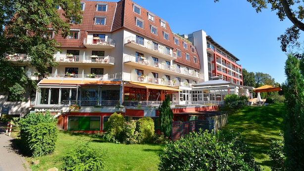 A multi-story hotel with balconies, a restaurant, and a well-maintained garden.