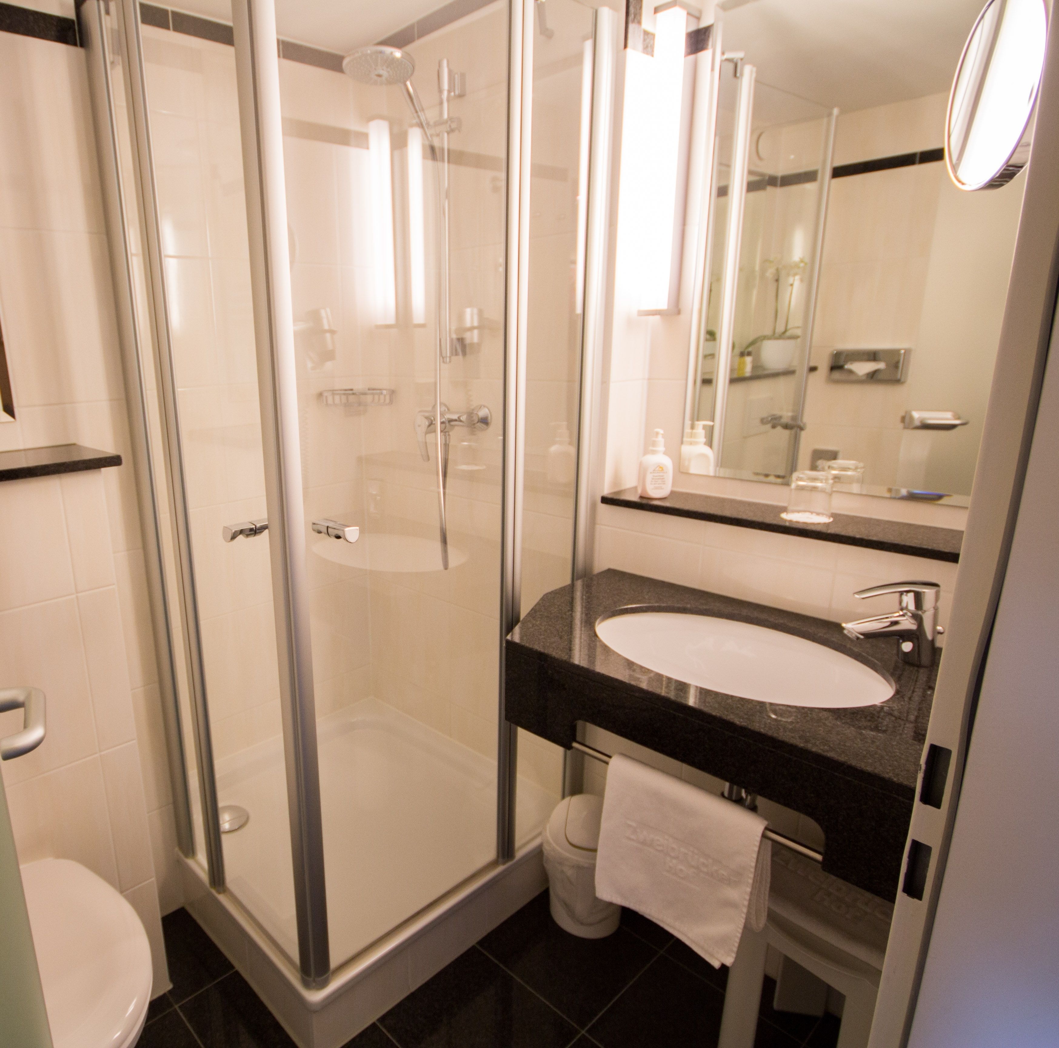 Een moderne badkamer met een douchecabine van glas, een witte wastafel en een grote spiegel.
