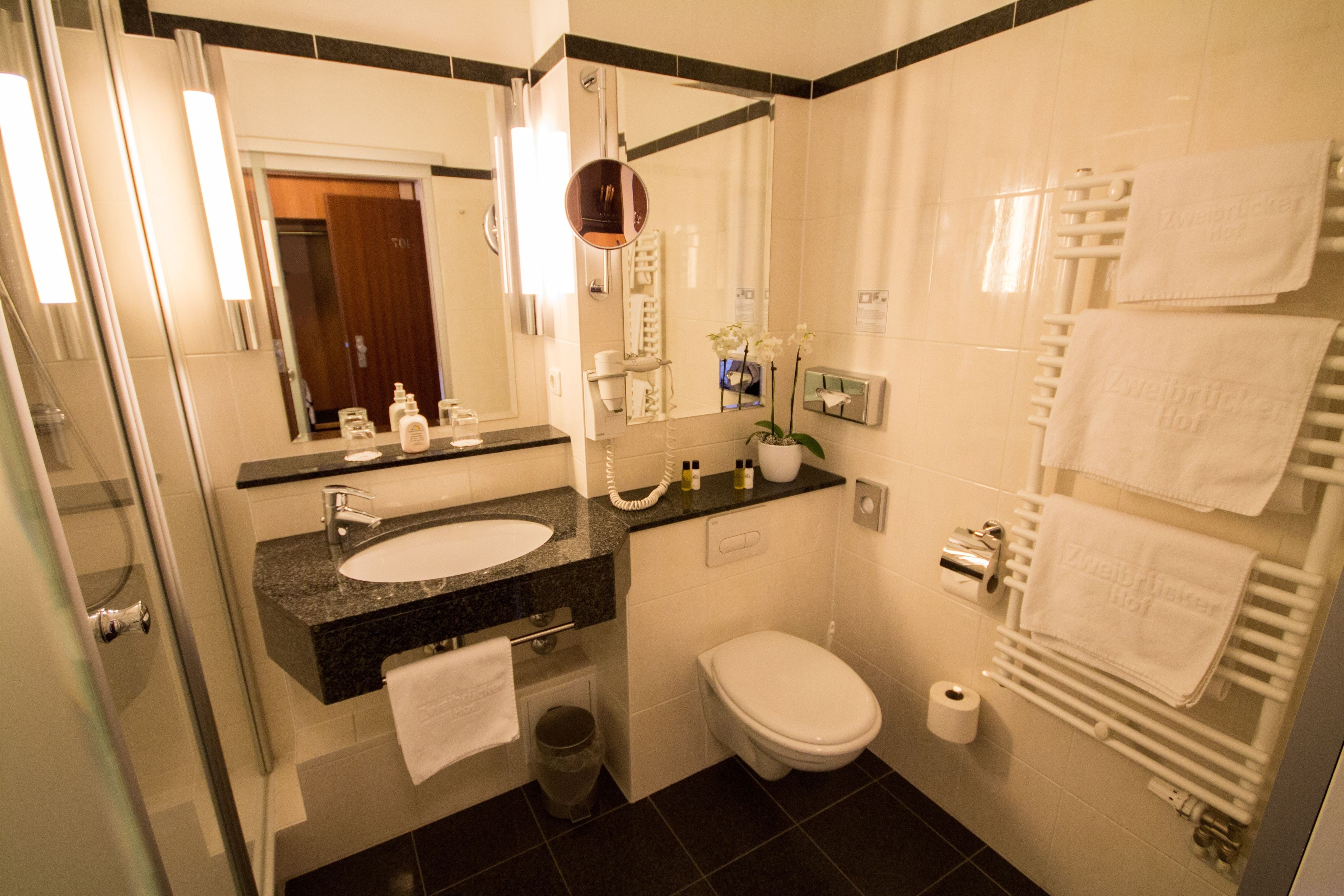 A modern bathroom with a sink, toilet, and a glass shower enclosure.