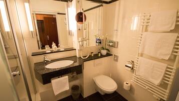 A modern bathroom with a sink, toilet, and a glass shower enclosure.