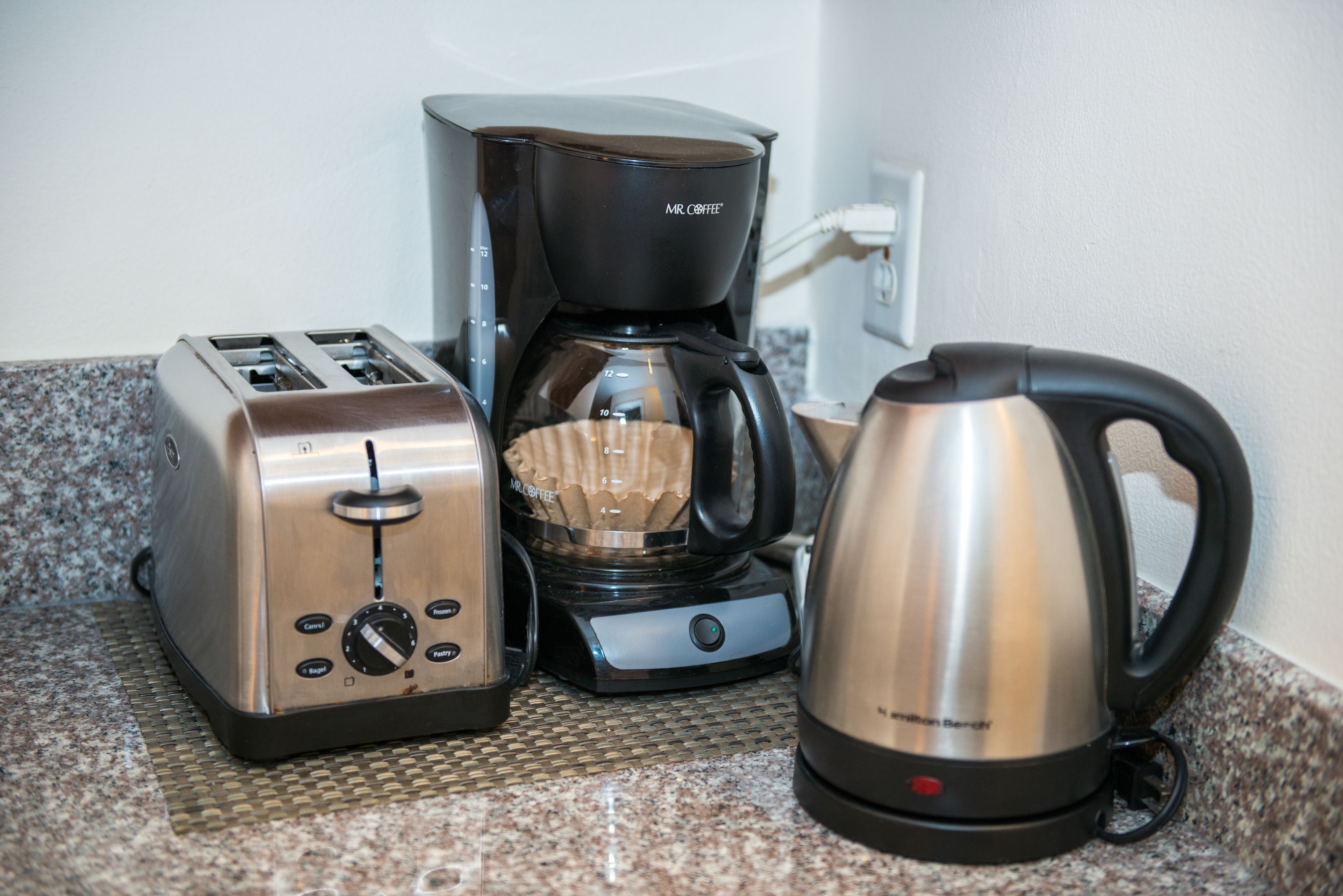 Un plan de travail de cuisine avec un grille-pain, une machine à café et une bouilloire.