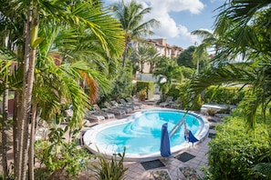 A swimming pool surrounded by palm trees and lounge chairs.