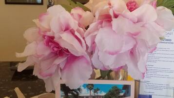 A reception area with a flower arrangement, a business card for Vivid Pink Photography, a postcard of Shore Haven Resort Inn, and a brochure.