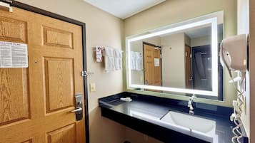 Un baño con puerta de madera, un lavabo, un espejo y un secador de pelo.