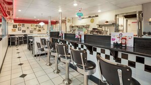 Un restaurante con mostrador, taburetes de bar y cartel de menú.