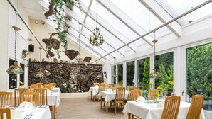 A restaurant with wooden tables and chairs, a stone wall, and hanging lights. - Hotel Zur Heidschnucke (Asendorf)