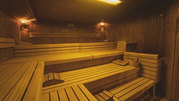 A sauna with wooden benches and walls, equipped with wall-mounted lights.