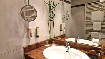 Een moderne badkamer met een marmeren wastafel, een spiegel en toiletartikelen.