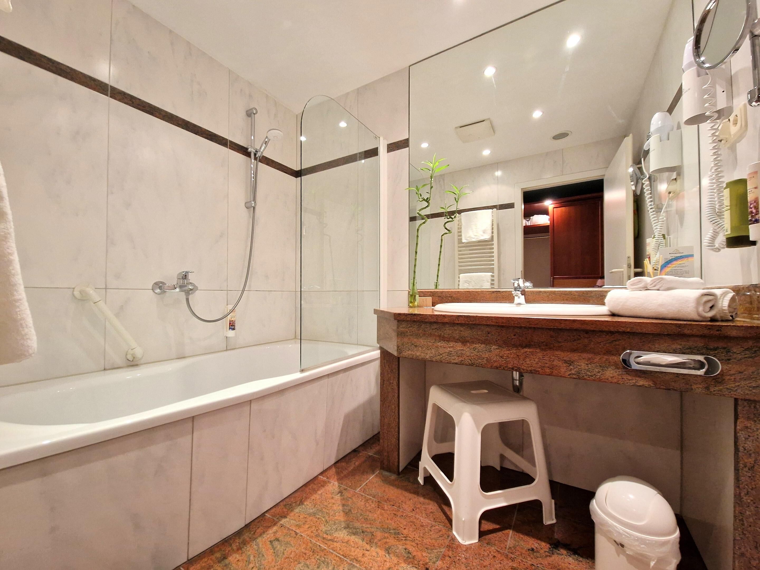 Un baño moderno con una bañera, cabina de ducha con mampara de vidrio, tocador con lavabo y un espejo.