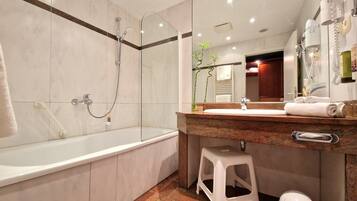 Un baño moderno con una bañera, cabina de ducha con mampara de vidrio, tocador con lavabo y un espejo.