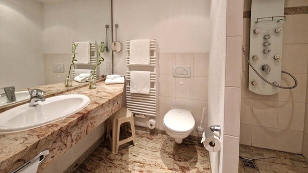 Une salle de bain moderne avec un lavabo en marbre, des toilettes, une douche et un miroir.
