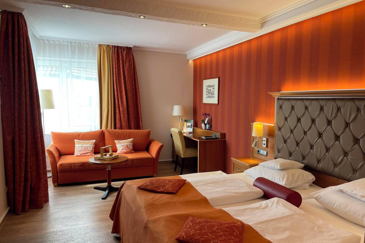 A hotel room with a bed, a sofa, a desk, and a chair.
