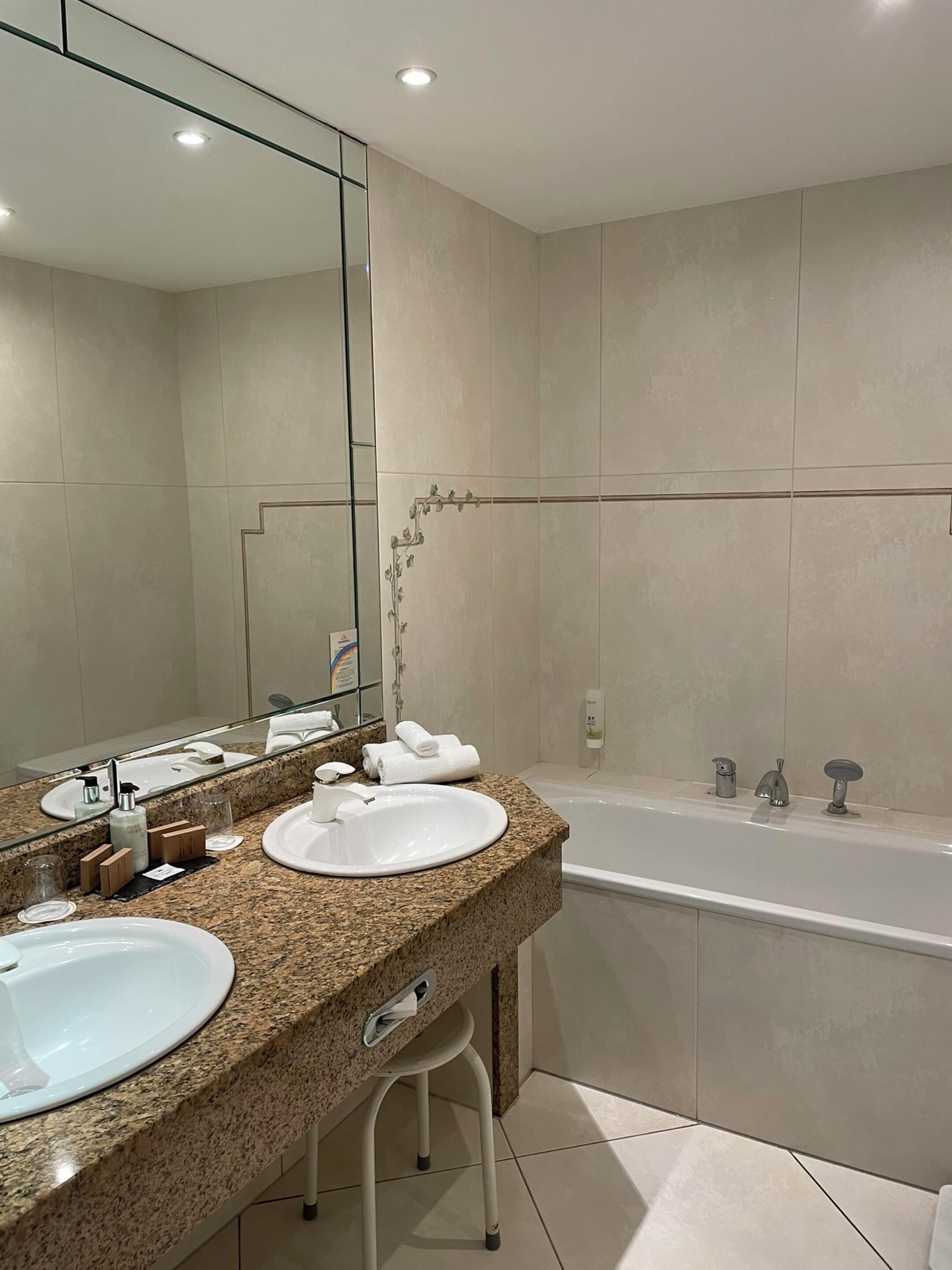 Une salle de bain moderne avec deux lavabos, un grand miroir et une baignoire.