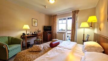Une chambre d’hôtel avec deux lits, un bureau avec une télévision, une chaise et une fenêtre avec des rideaux.