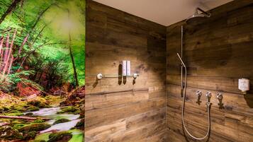 A bathroom with wooden walls, a shower, and a wall-mounted towel rack.