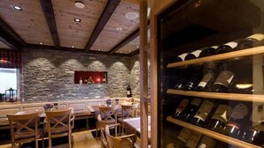 A cozy restaurant with stone walls, wooden ceiling beams, and a wine rack filled with bottles. - Germanenhof (Steinheim)