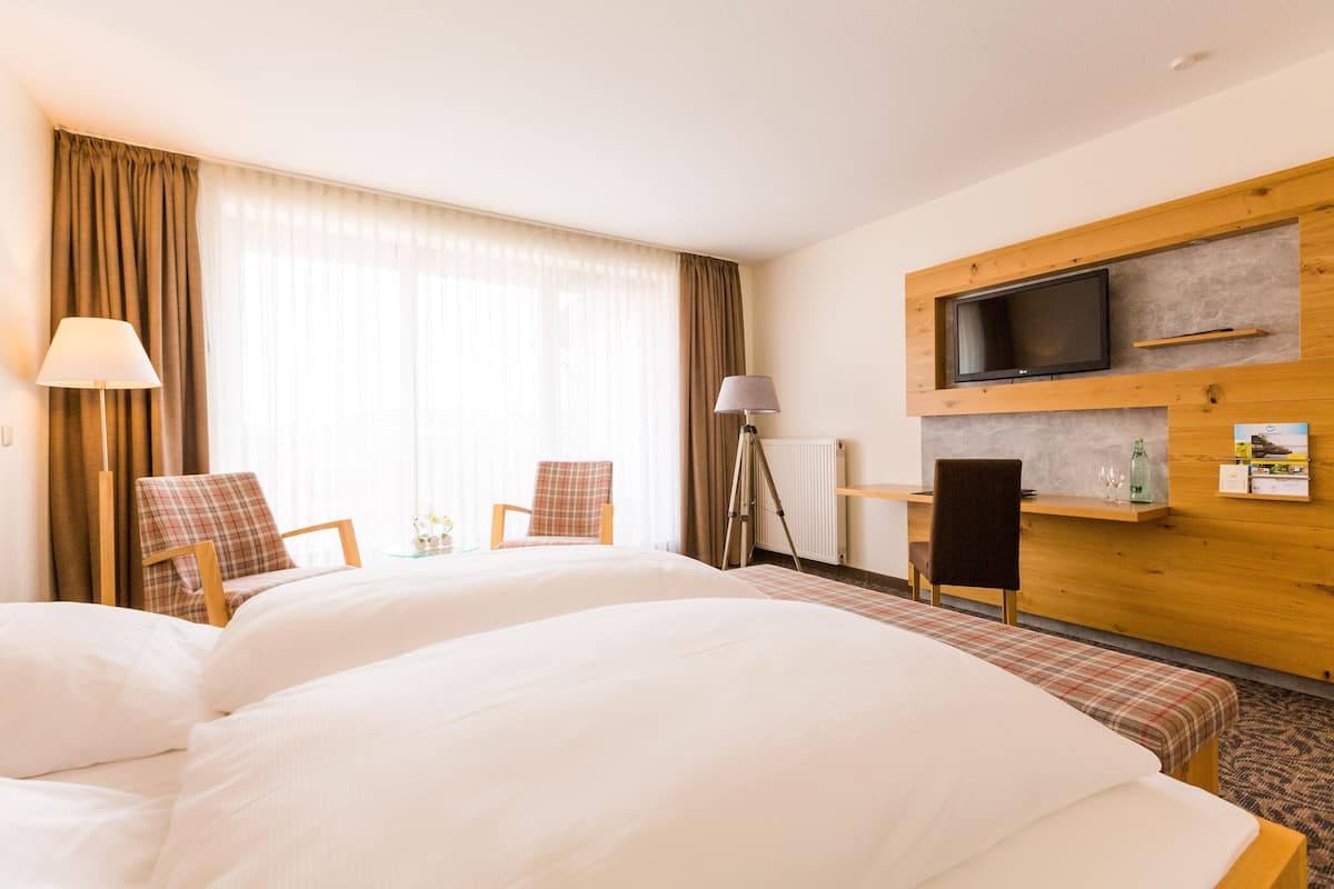 A hotel room with two beds, a television, a desk, and a chair.