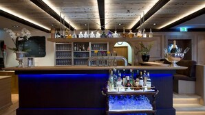 A bar area with a wooden ceiling, shelves with bottles, a chalkboard menu, and a bar counter with glasses. - Germanenhof (Steinheim)