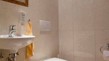 Un baño con lavamanos, inodoro y espejo.