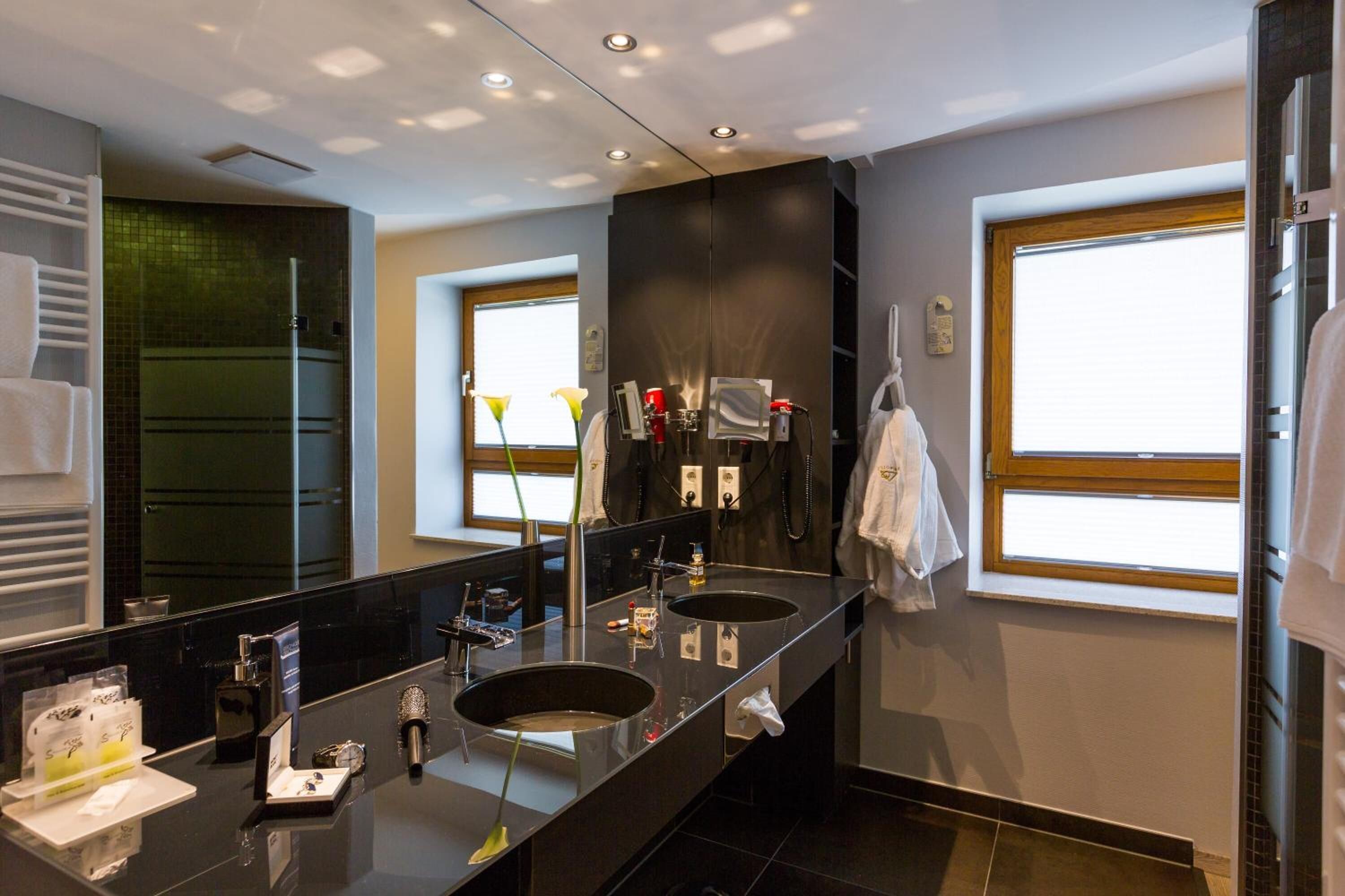 Un baño moderno con lavamanos dobles, un espejo grande y un ventanal que proporciona luz natural.