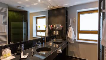 Un baño moderno con lavamanos dobles, un espejo grande y un ventanal que proporciona luz natural.