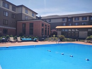 Una piscina al aire libre de temporada, sombrillas