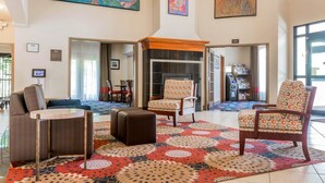 A spacious lobby with a patterned rug, seating area, and a fireplace. - Comfort Inn & Suites South Burlington near University (South Burlington)