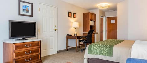 A hotel room with a bed, a desk with a chair, a television, and a dresser.