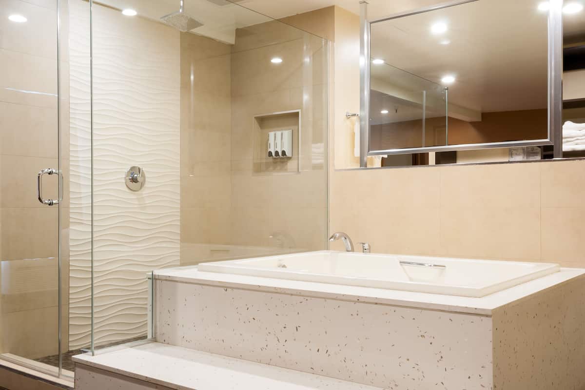 A modern bathroom with a glass shower enclosure, a large freestanding bathtub, and a wall-mounted mirror.